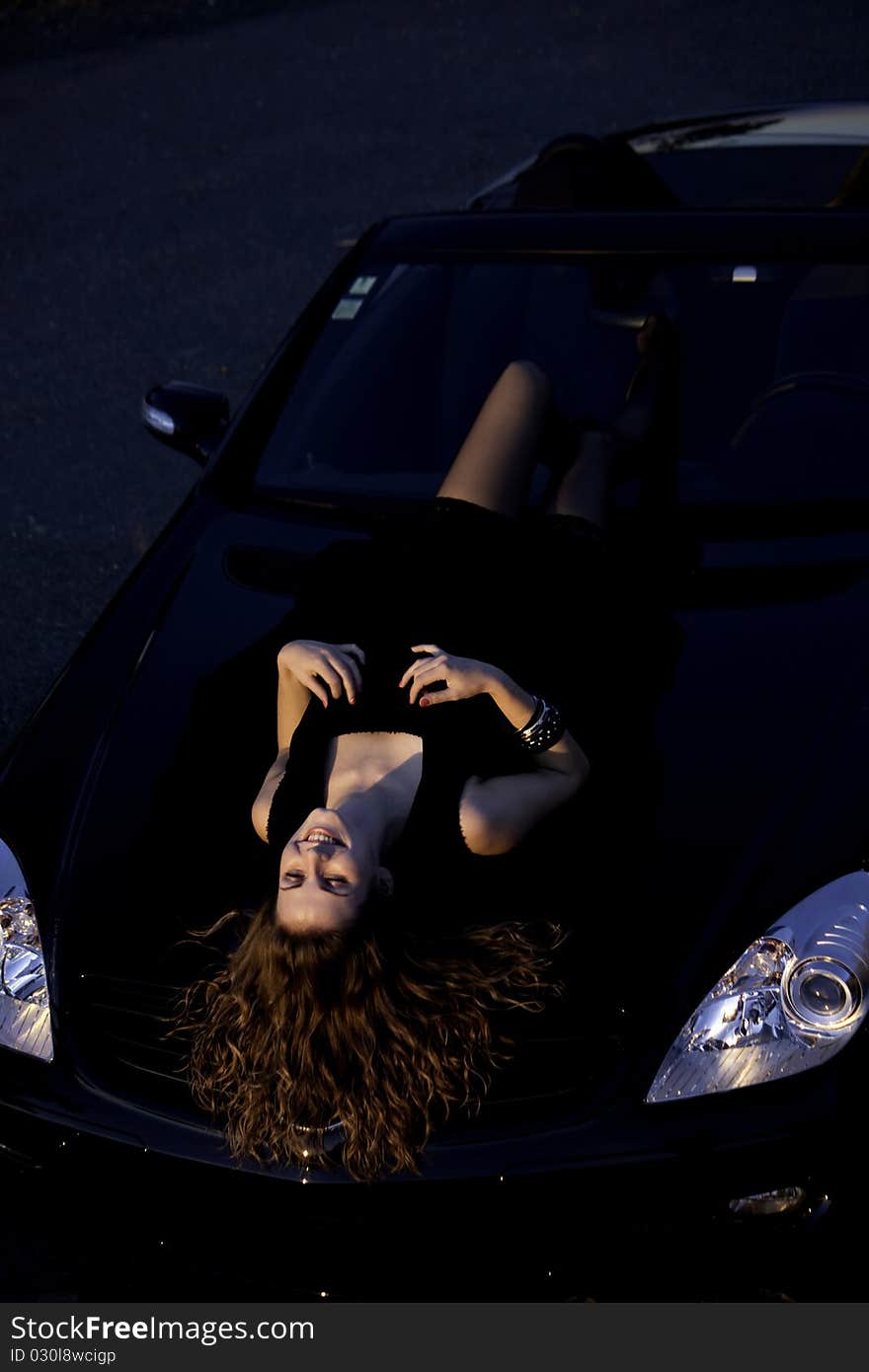 View of a beautiful woman on top of a sports car. View of a beautiful woman on top of a sports car.