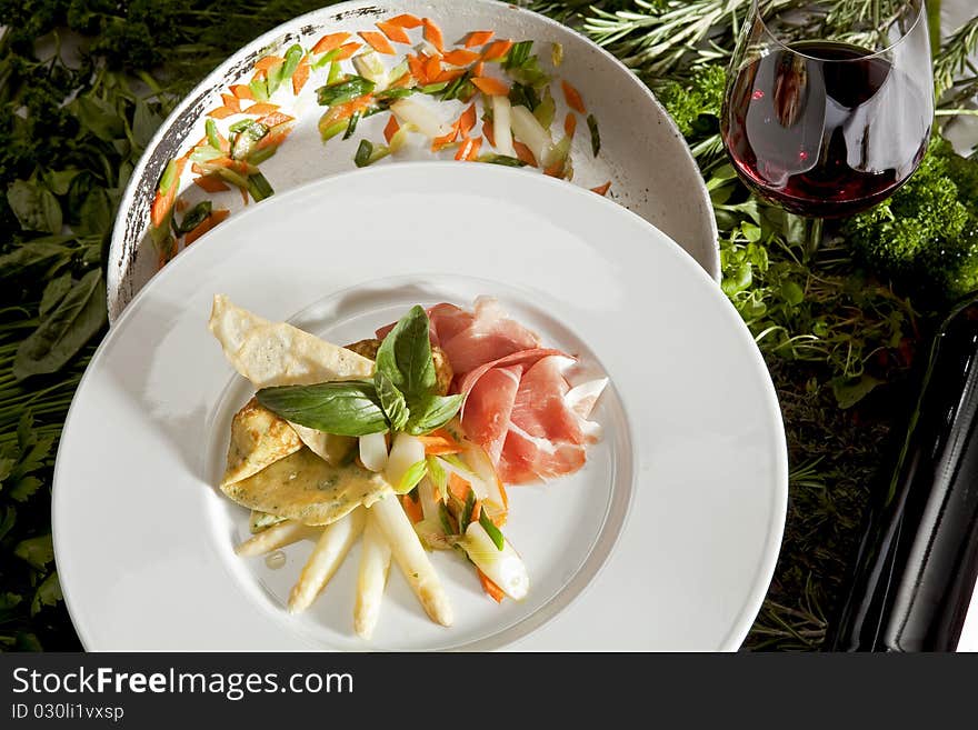 Herb pancakes with asparagus on a white plate with a glass of red wine