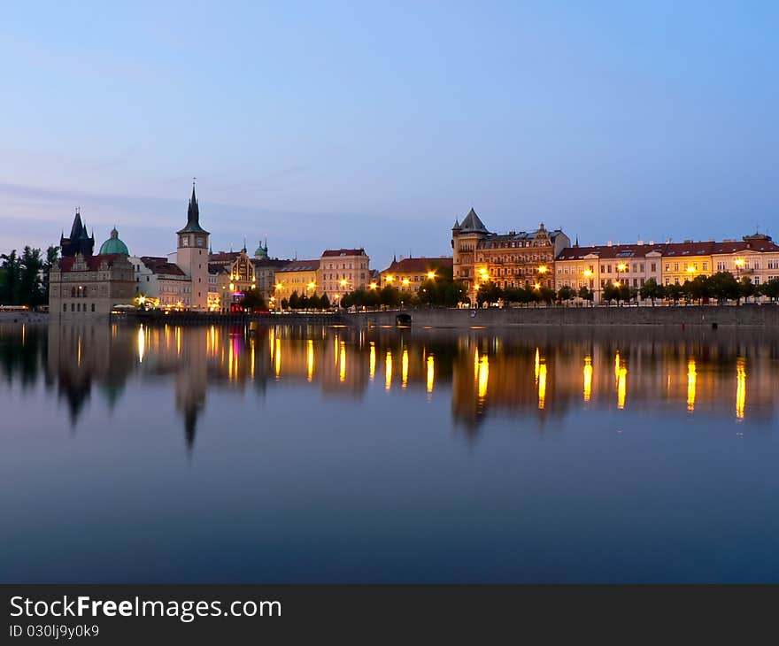 Prague riverbank on sunset with reflection on water