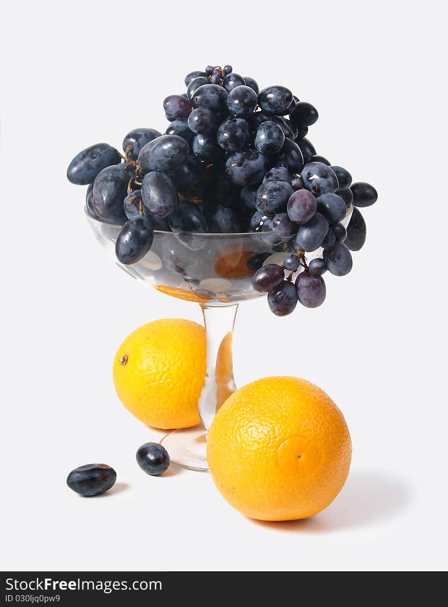 Black grapes in a vase and oranges