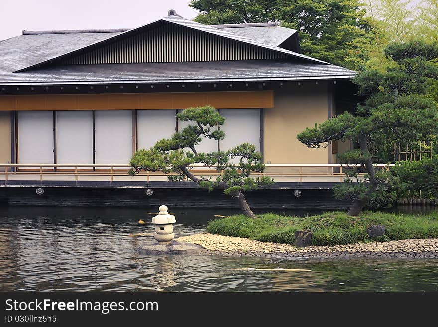 Quiet Japanese pond with pine tree, small lantern and tea house on backward, Tokyo