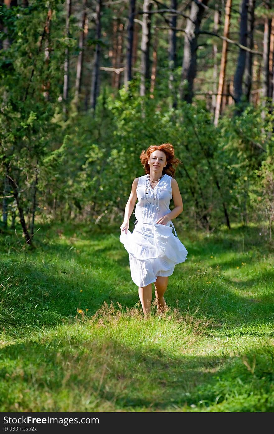 Red-haired woman running on path in the wood. Red-haired woman running on path in the wood