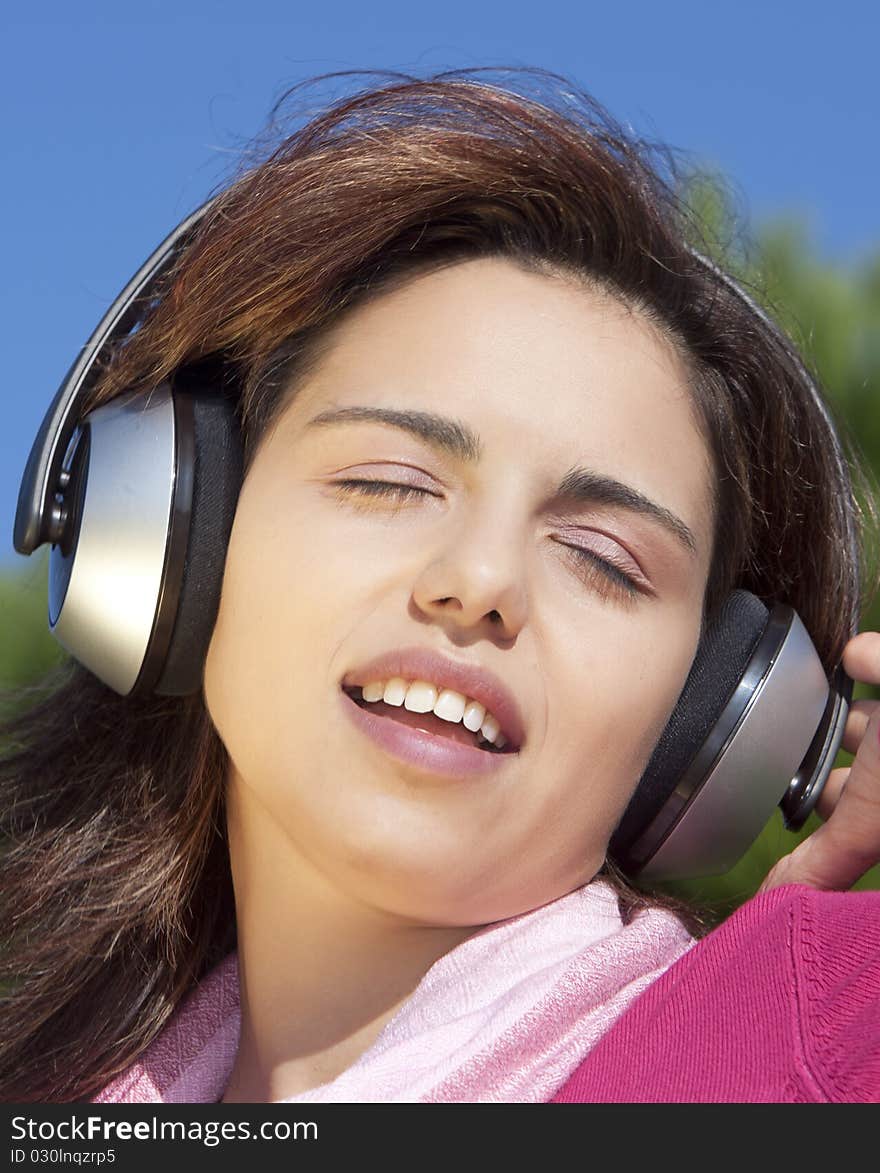 Pretty young girl listening music in the park