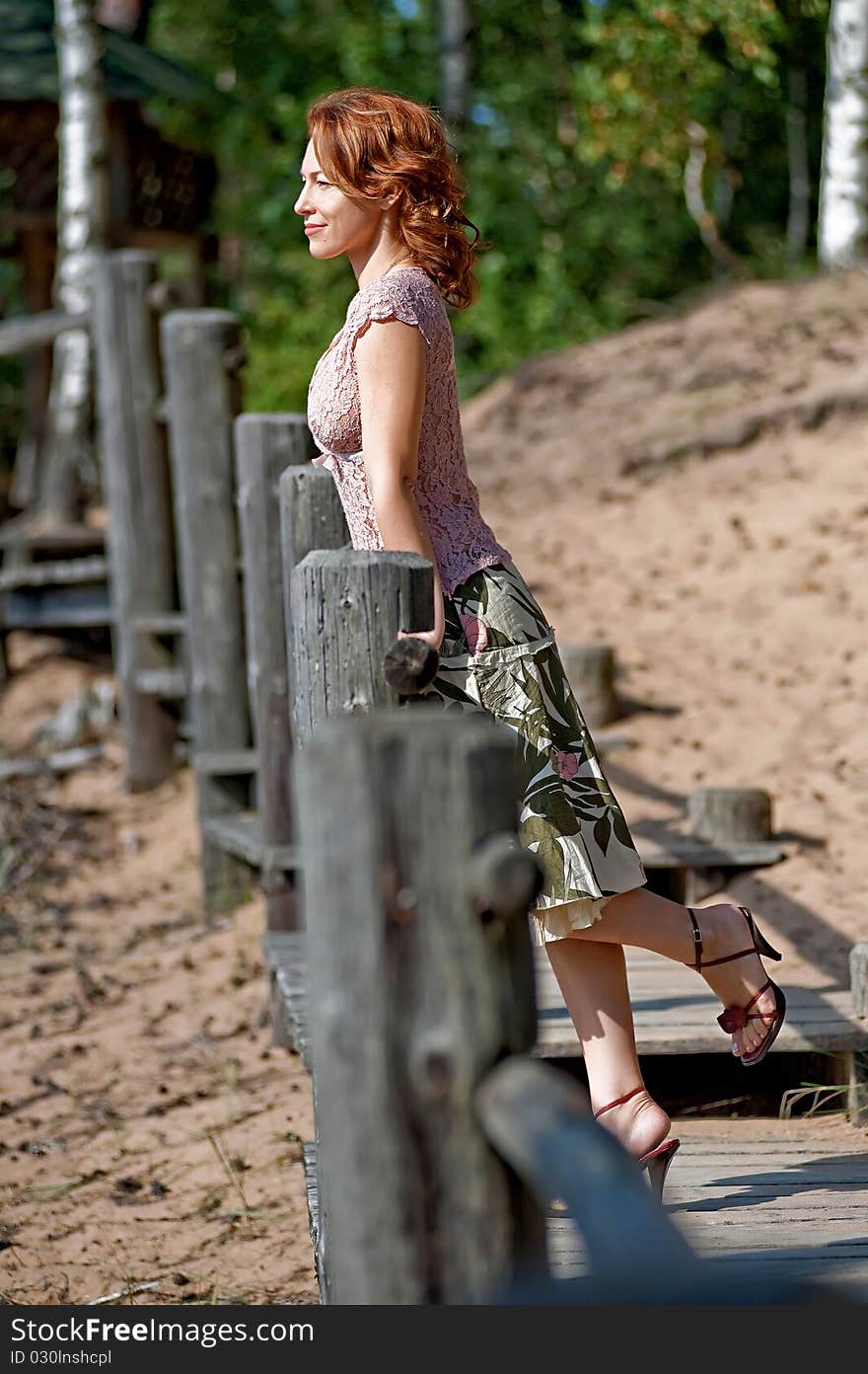 Red-haired adult woman in dune looking at the sea