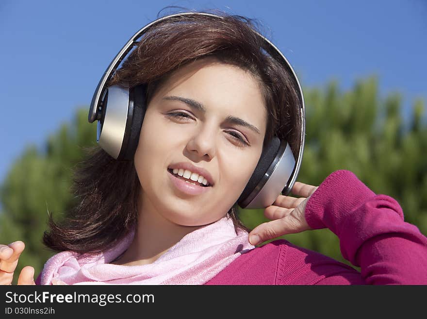 Pretty young girl listening music in the park