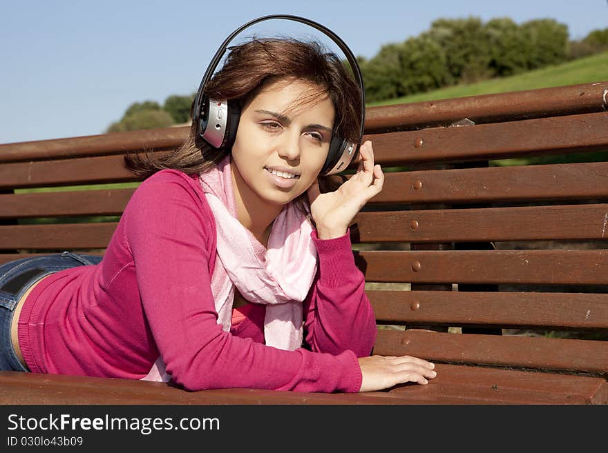 Pretty young girl listening music in the park