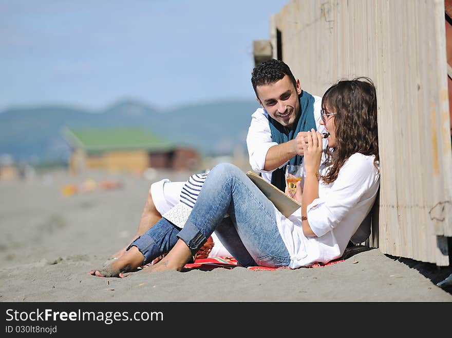 Happy young couple enjoying picnic on the beach and have good time on summer vacations. Happy young couple enjoying picnic on the beach and have good time on summer vacations