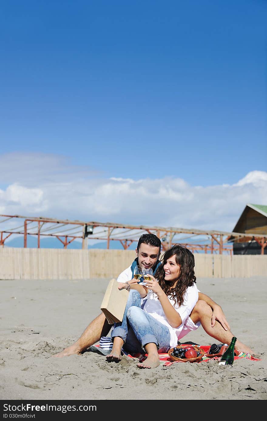 Happy young couple enjoying picnic on the beach and have good time on summer vacations. Happy young couple enjoying picnic on the beach and have good time on summer vacations