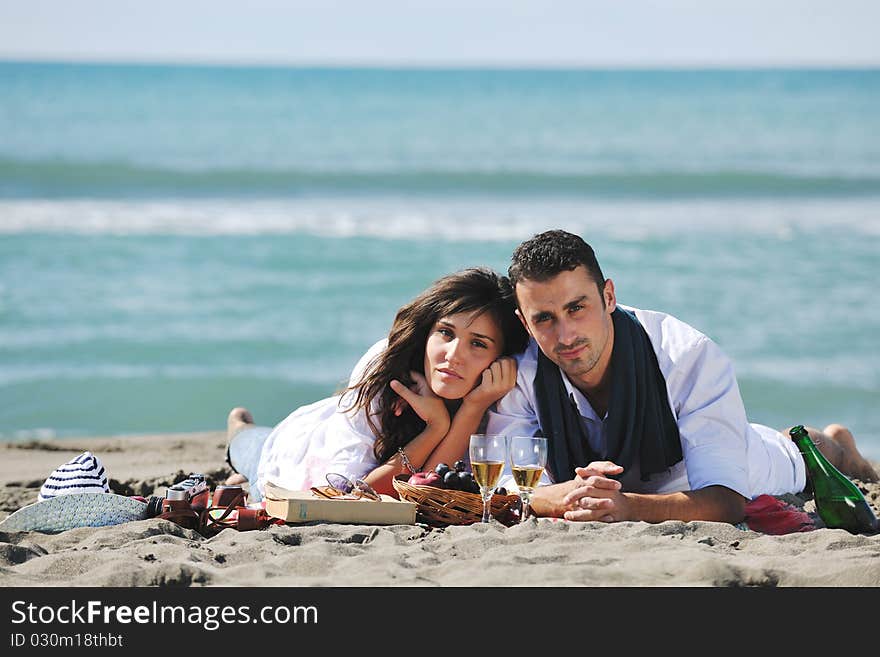 Happy young couple enjoying picnic on the beach and have good time on summer vacations. Happy young couple enjoying picnic on the beach and have good time on summer vacations