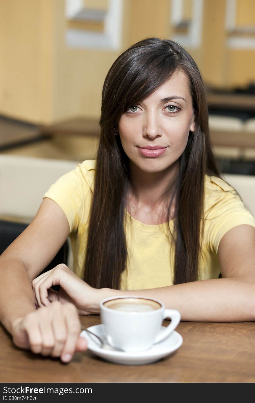 Young beautiful girl posing across table with cup of coffee. Young beautiful girl posing across table with cup of coffee