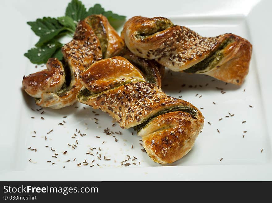 Fresh spinach pastry with sesame seeds and cumin seeds on white plate