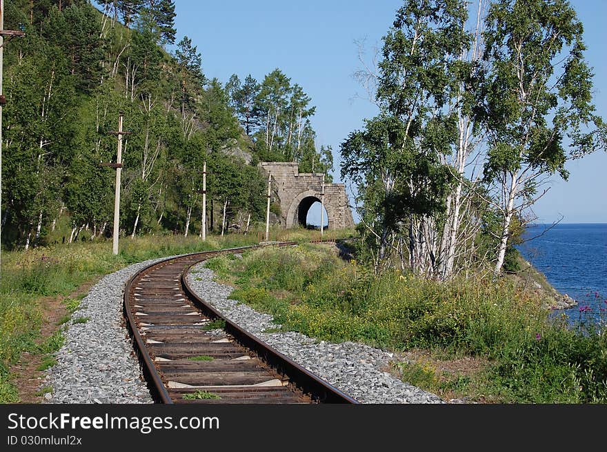 Railroad along the shore of the lake, disappearing into the tunnel. Railroad along the shore of the lake, disappearing into the tunnel