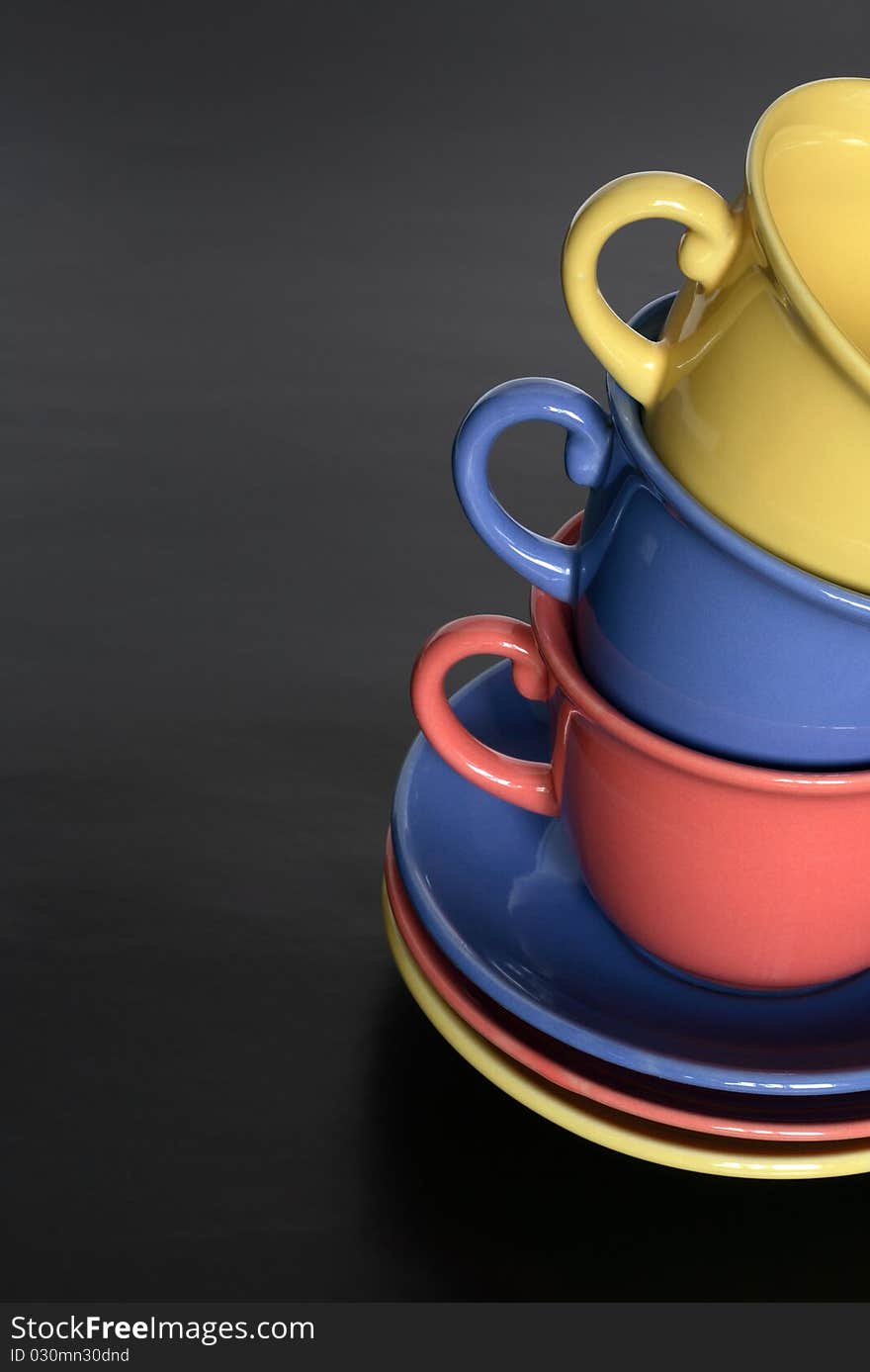 Stack of three motley cups standing on black background with copy space. Stack of three motley cups standing on black background with copy space