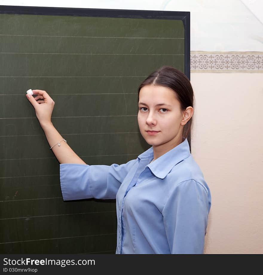 Girl schoolgirl wrote in chalk on a blackboard