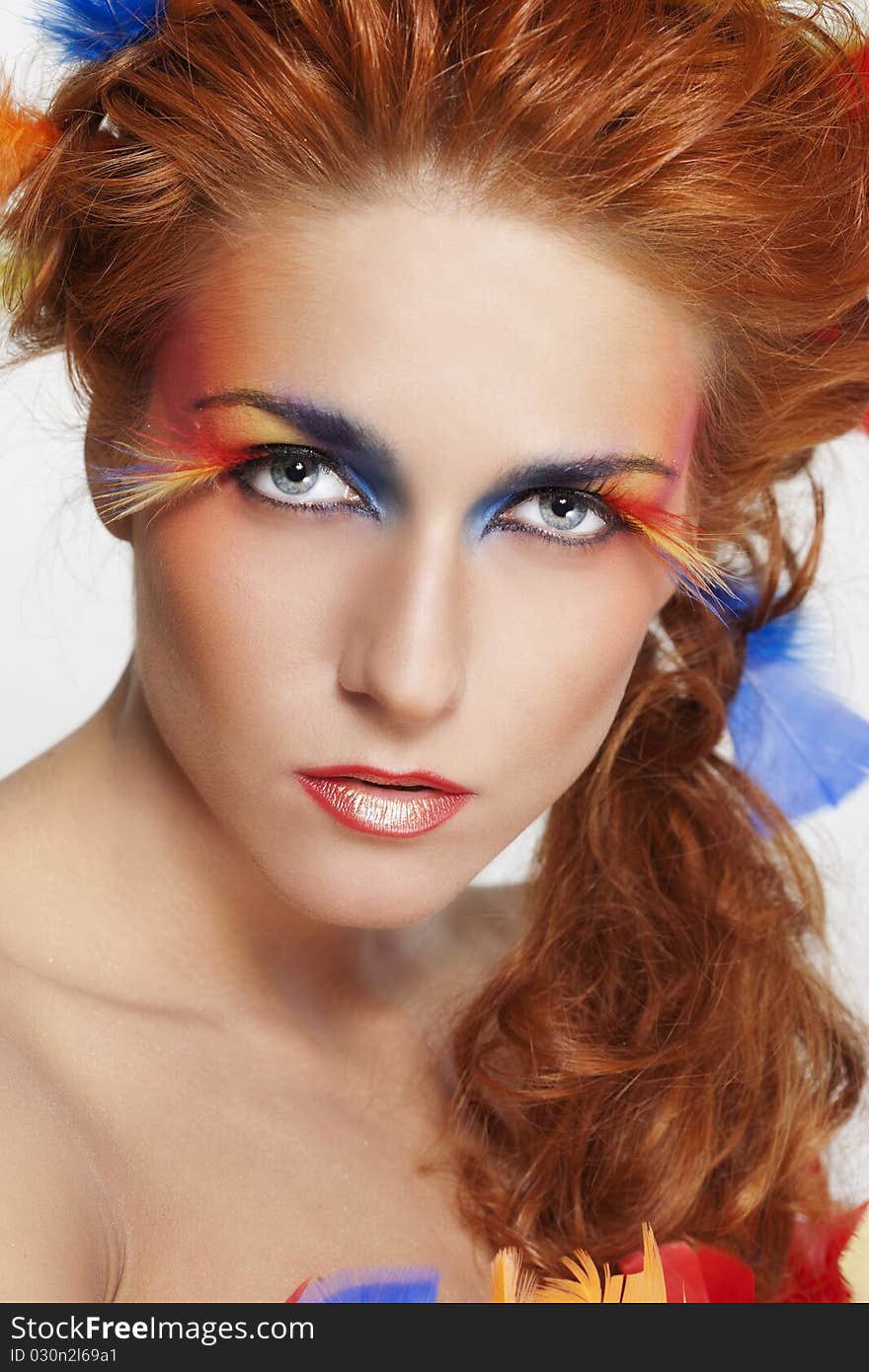 Beautiful woman with face framed in feathers with bright makeup and long faux lashes