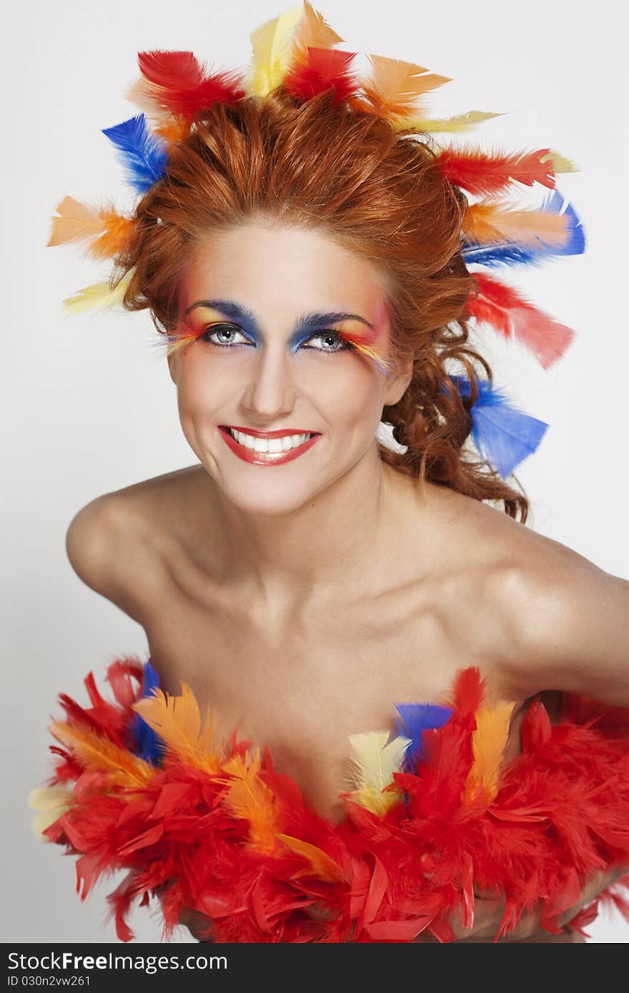 Beautiful woman with face framed in feathers with bright makeup and long faux lashes