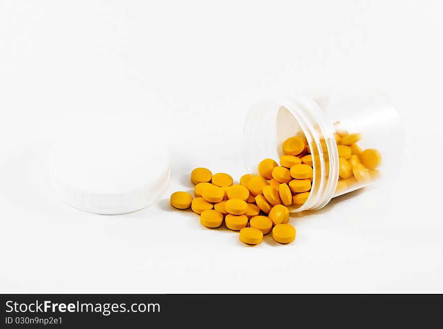 Pot of yellow pills on a light background