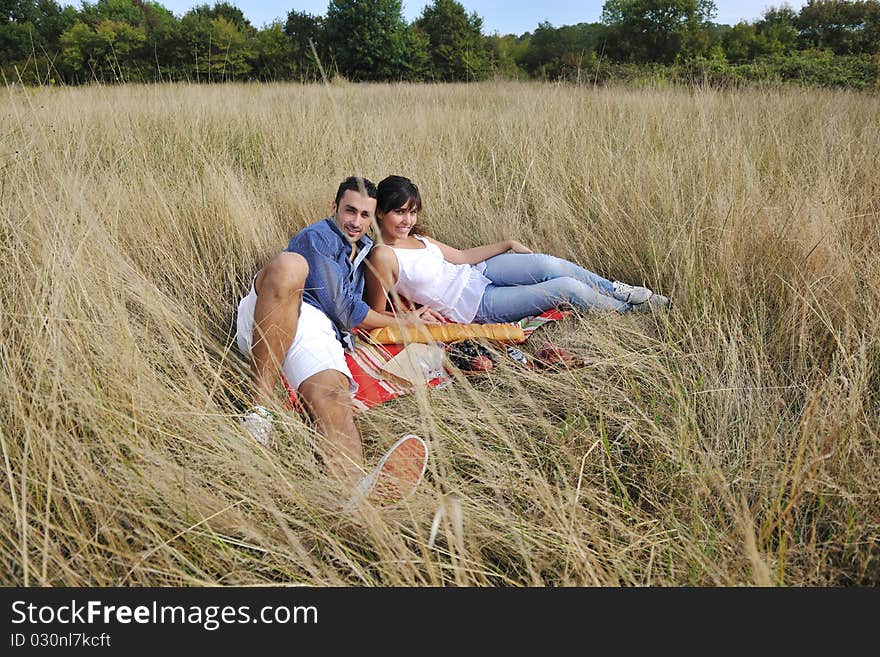 Happy young couple enjoying picnic on the countryside in the field and have good time. Happy young couple enjoying picnic on the countryside in the field and have good time