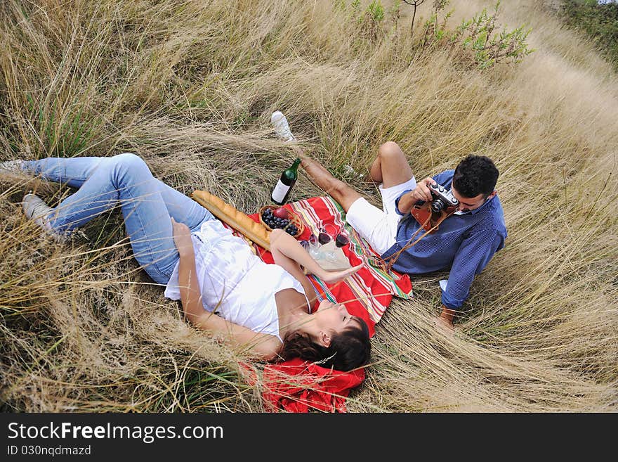 Happy young couple enjoying picnic on the countryside in the field and have good time. Happy young couple enjoying picnic on the countryside in the field and have good time