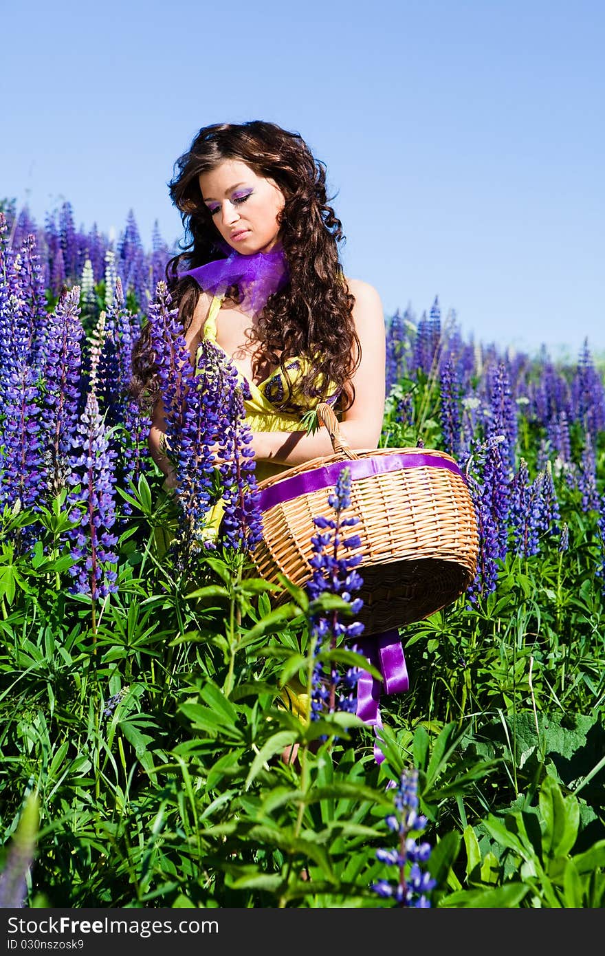 Portrait of young woman in plant of violet wild lupine