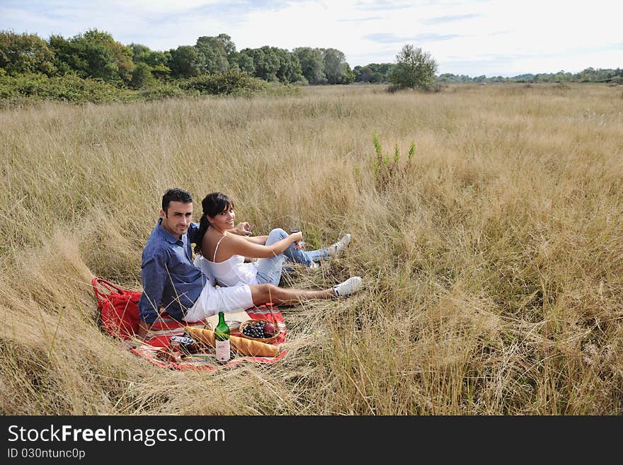 Happy young couple enjoying picnic on the countryside in the field and have good time. Happy young couple enjoying picnic on the countryside in the field and have good time