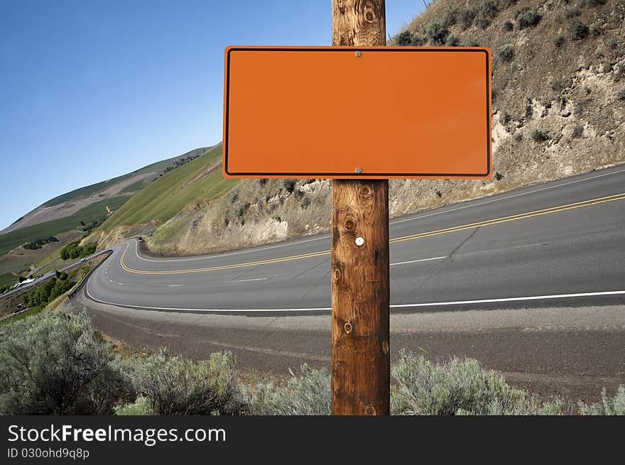 Blank orange construction sign on wooden pole, outdoor day time asphalt highway on background. Blank orange construction sign on wooden pole, outdoor day time asphalt highway on background