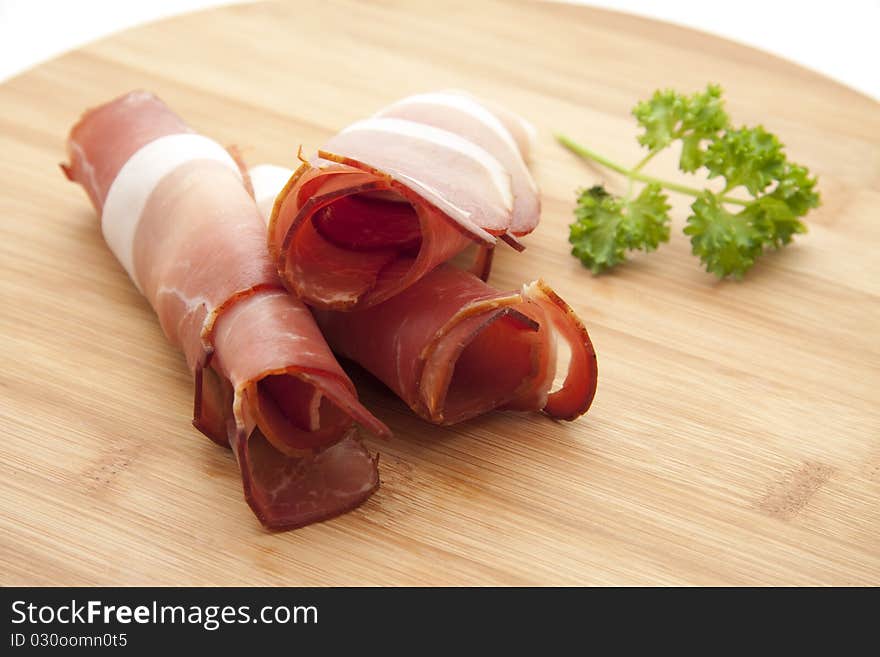 Raw ham and parsley onto wood plates. Raw ham and parsley onto wood plates