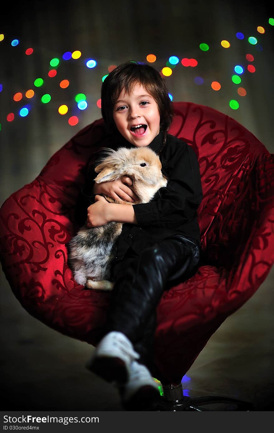 Smiling boy sitting and holding a rabbit. Smiling boy sitting and holding a rabbit