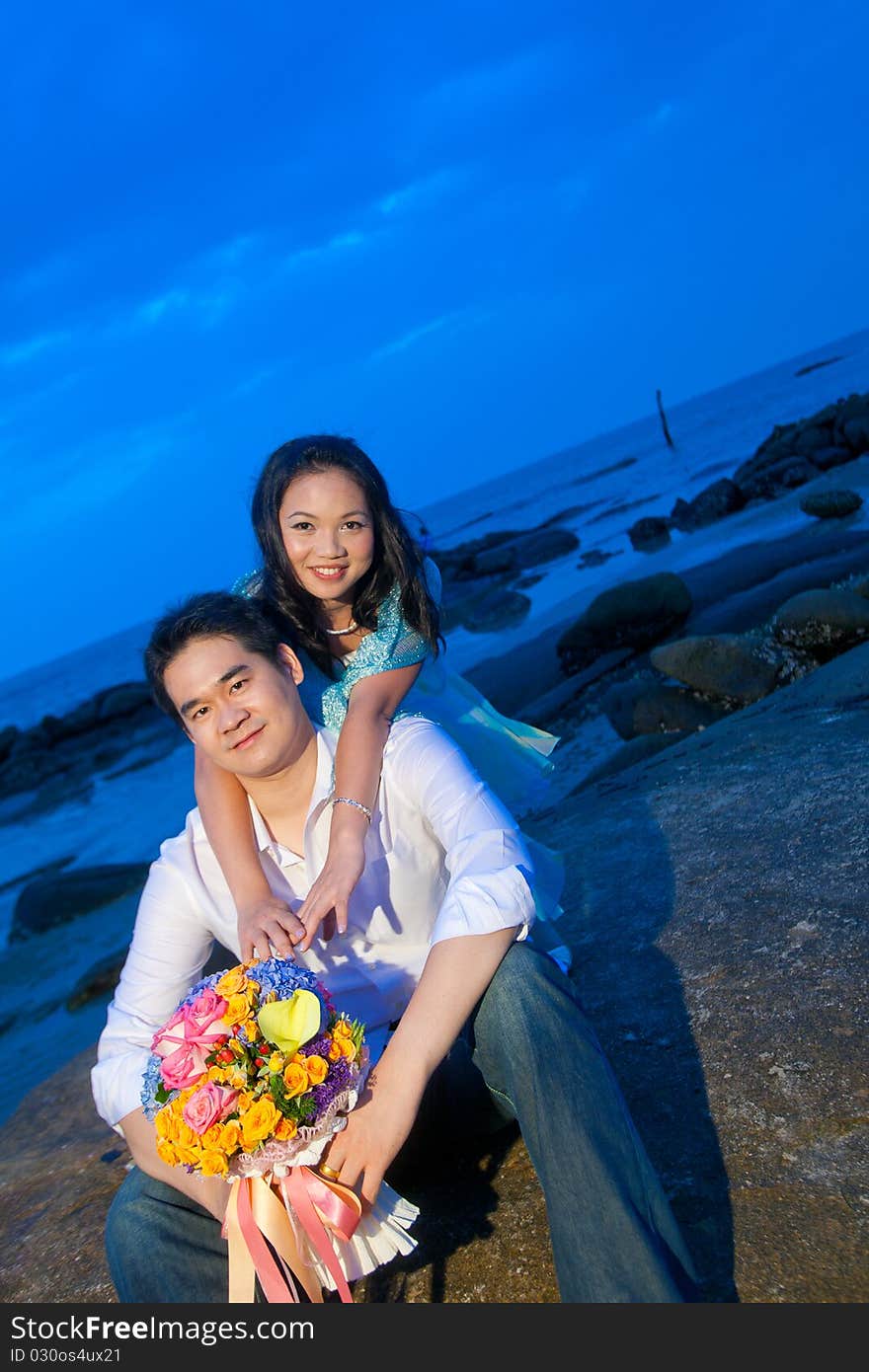 Attractive young girl embracing her handsome boyfriend on the beach at dusk. Attractive young girl embracing her handsome boyfriend on the beach at dusk