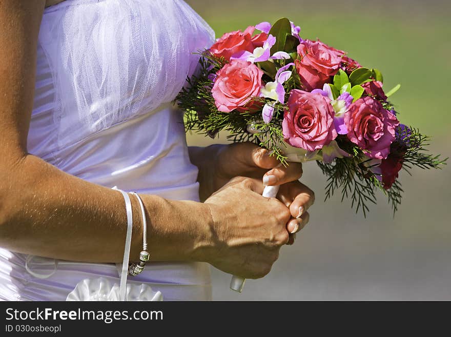 A closeup shot of a bride holding a beautiful bouquet of red and pink flowers on her wedding day. A closeup shot of a bride holding a beautiful bouquet of red and pink flowers on her wedding day