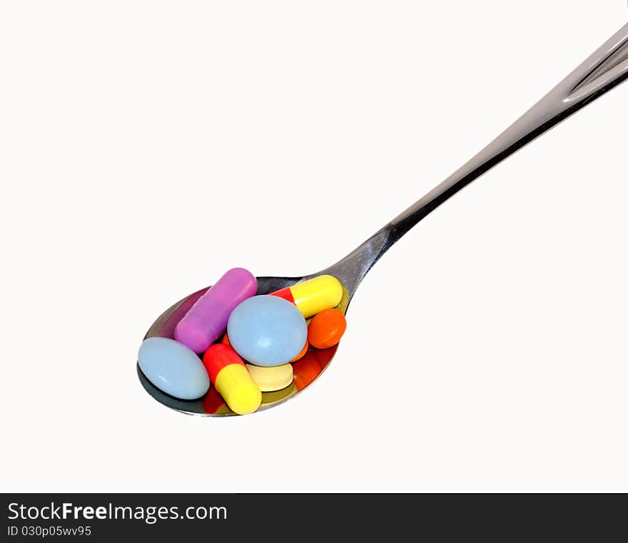 Multi-colored tablets in a steel spoon. Multi-colored tablets in a steel spoon