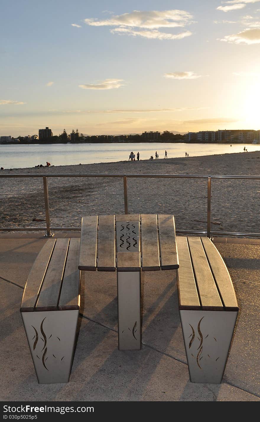 Sun setting at the beach with bench and table int he foreground. Sun setting at the beach with bench and table int he foreground