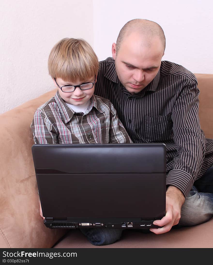 Father son sitting on the couch with a computer