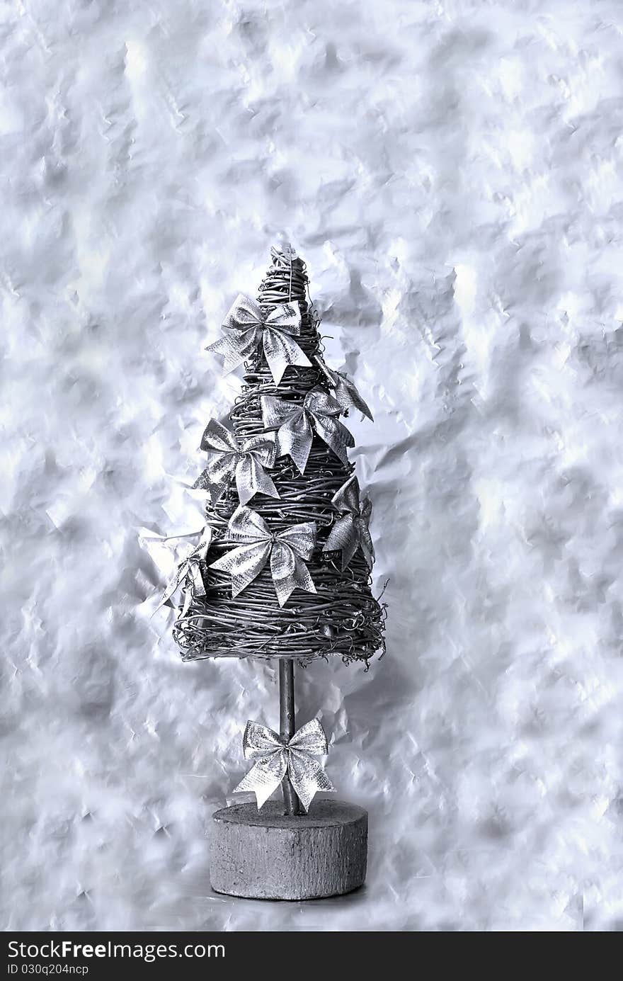 Silver christmas tree with decorative bows on the abstract background