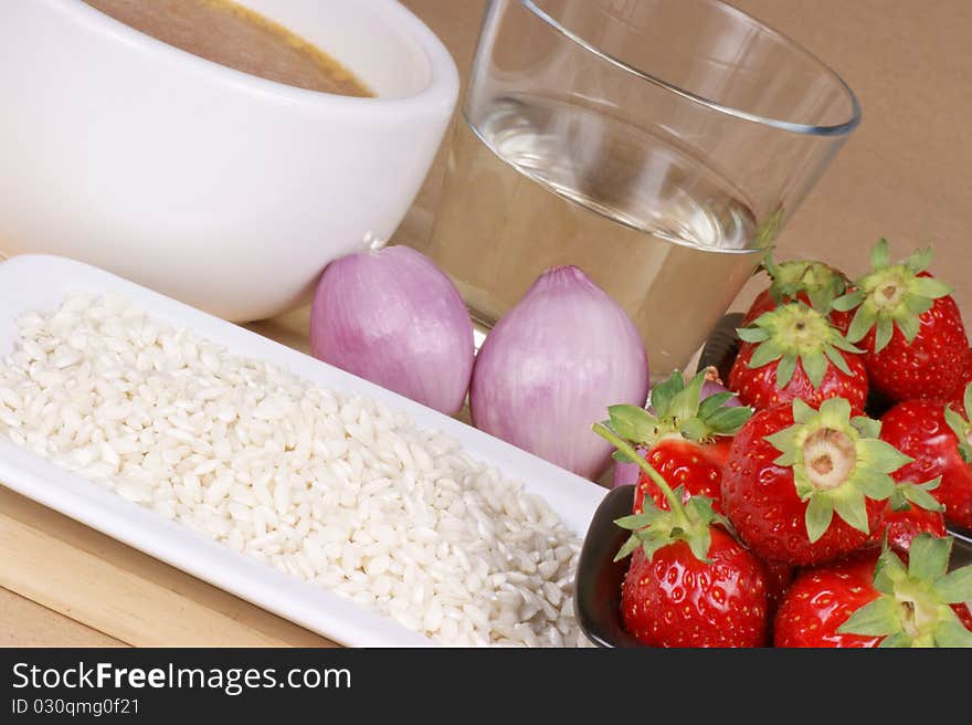 Ingredients for risotto with strawberries: white rice, strawberries, onion, white wine and vegetable stock. Studio shot over light brown background. Selective focus, shallow DOF. Ingredients for risotto with strawberries: white rice, strawberries, onion, white wine and vegetable stock. Studio shot over light brown background. Selective focus, shallow DOF