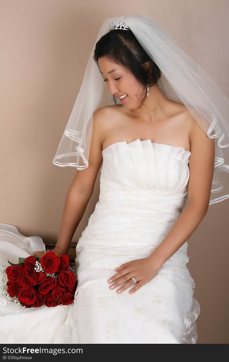 Beautiful bride wearing a traditional gown with red roses