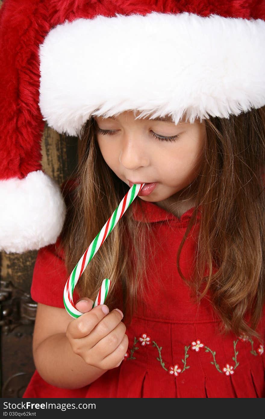 Beautiful brunette christmas girl eating a candy cane