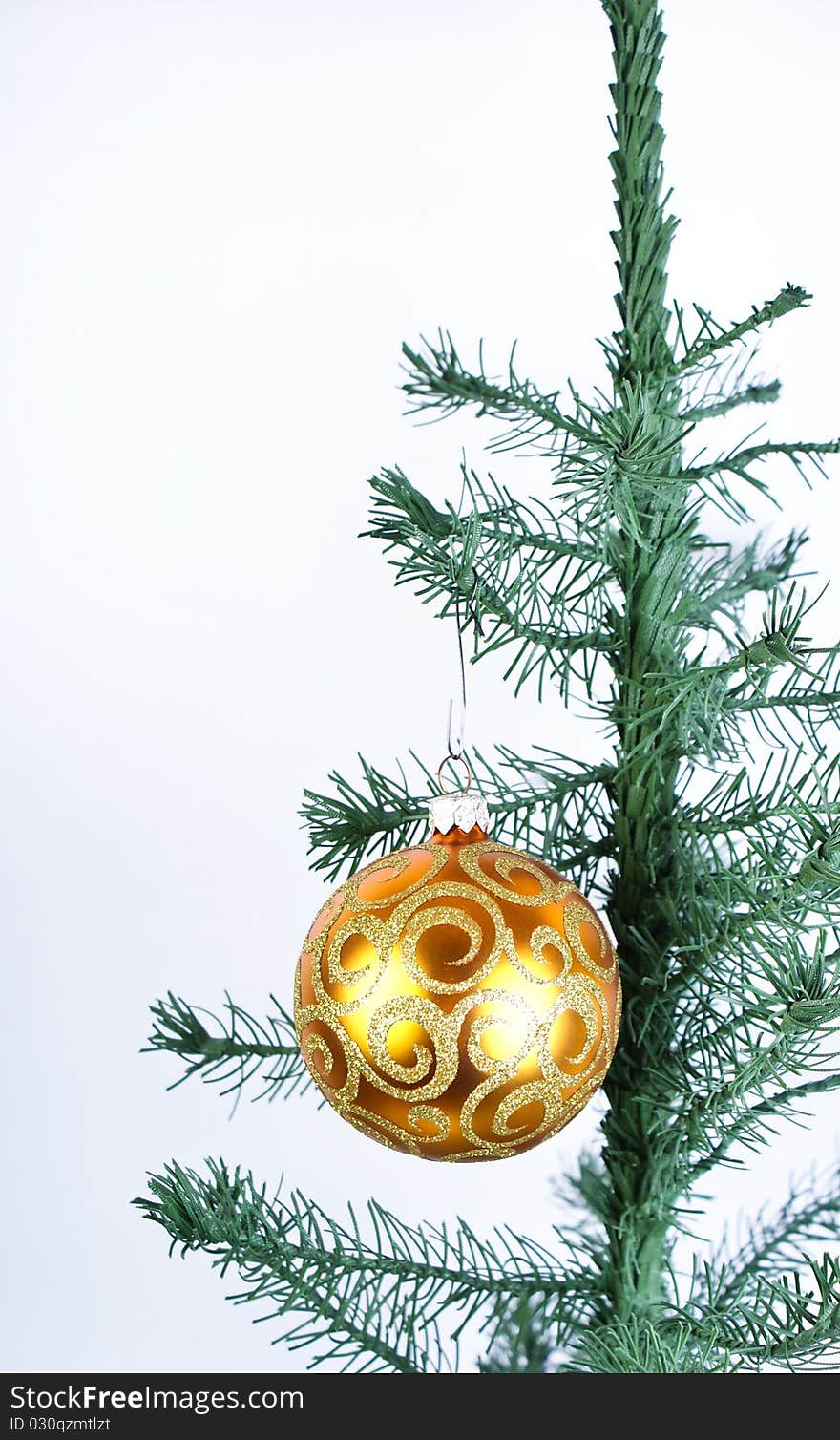 Golden ball on fir-tree on white background