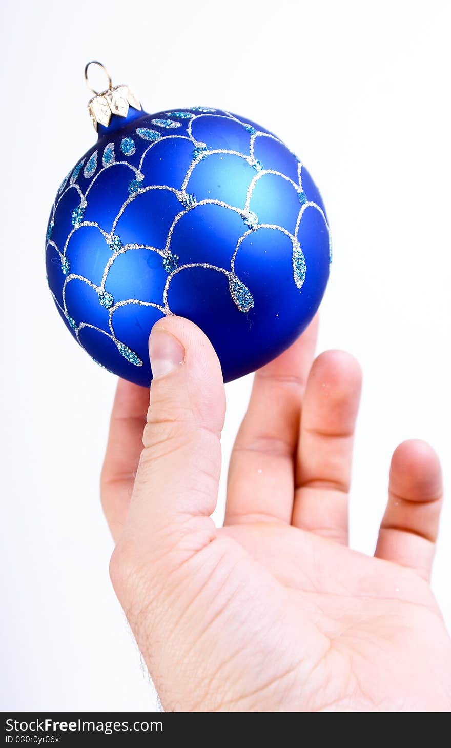 Hand holding a blue christmas ball on white