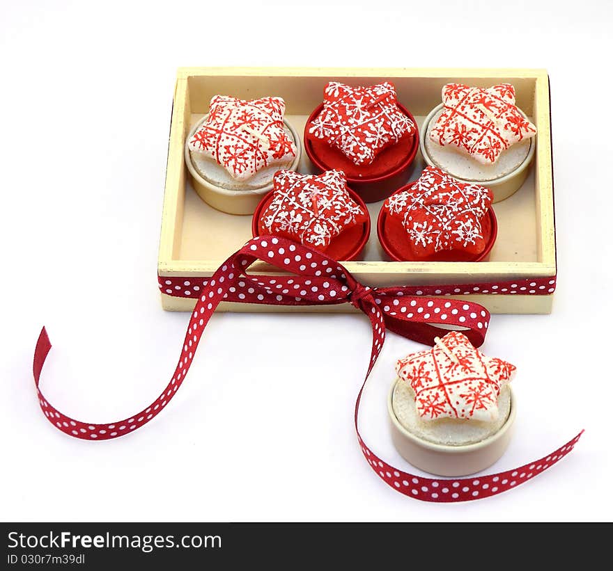 The wooden box with multi-colored candles is packed by a red tape. The wooden box with multi-colored candles is packed by a red tape