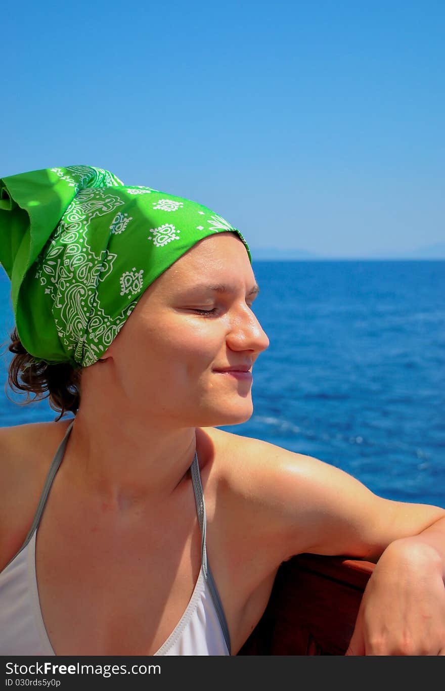 Young woman in soft focus relaxing near the sea, with eyes close and a green bandana. Young woman in soft focus relaxing near the sea, with eyes close and a green bandana