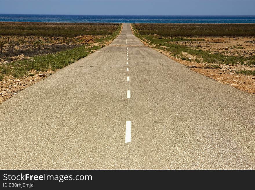 Straight road going through farmland in rural Socotra, Yemen.