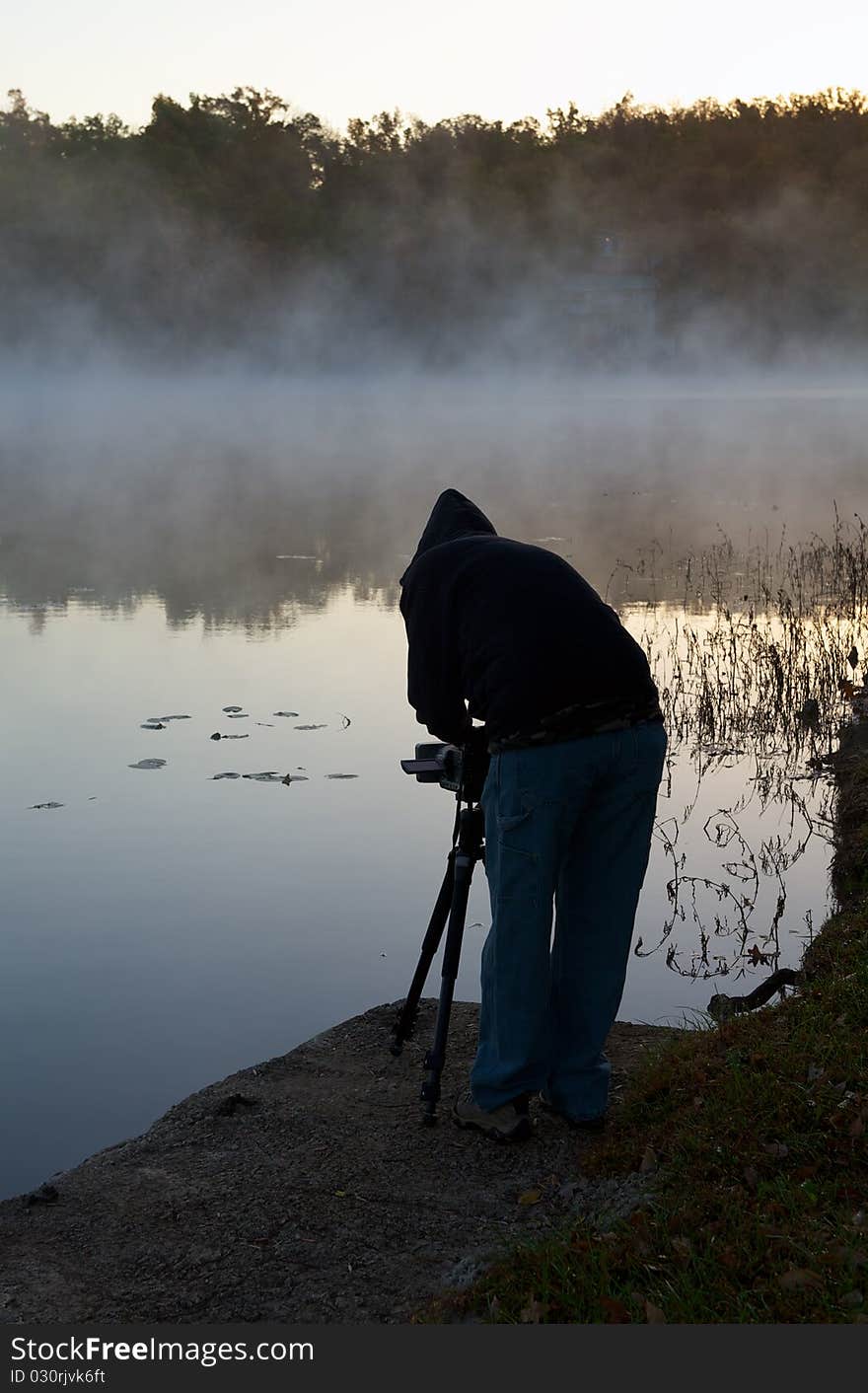 Professional photographer filming moving fog across early morning lake. Professional photographer filming moving fog across early morning lake