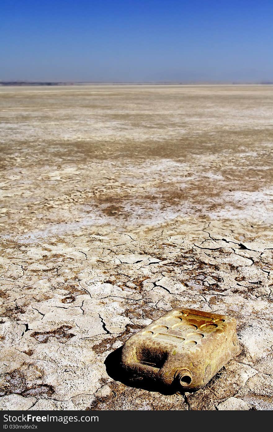 Old plastic jerry can  in front of dry cracked earth background with a warm tone. Old plastic jerry can  in front of dry cracked earth background with a warm tone