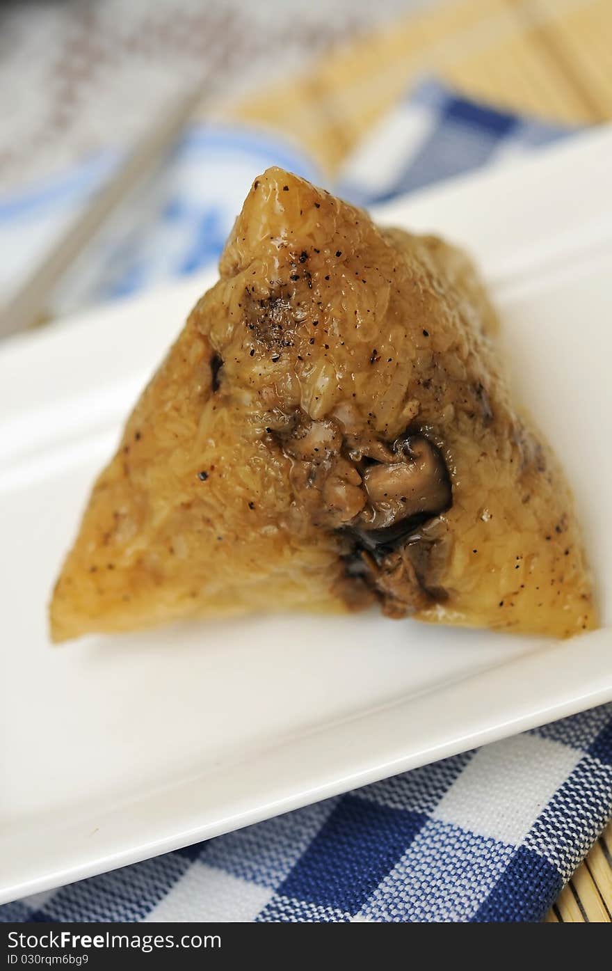 Unwrapped dumpling on white plate showing glutinous rice texture.