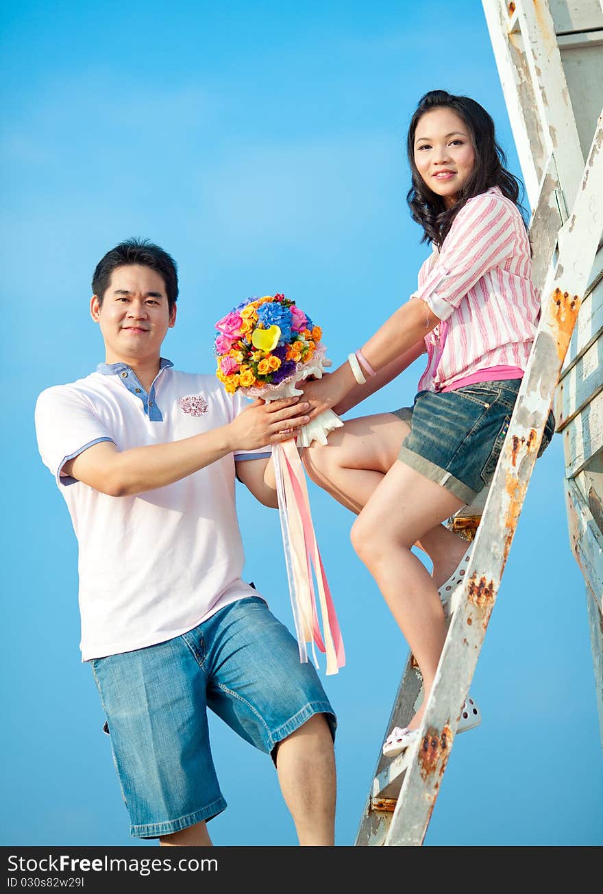 Couple holding beautiful flowers bouquet together on the beach