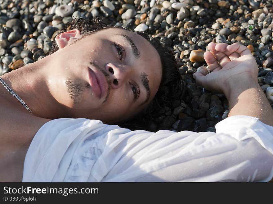 Young man lies on seacoast on pebble