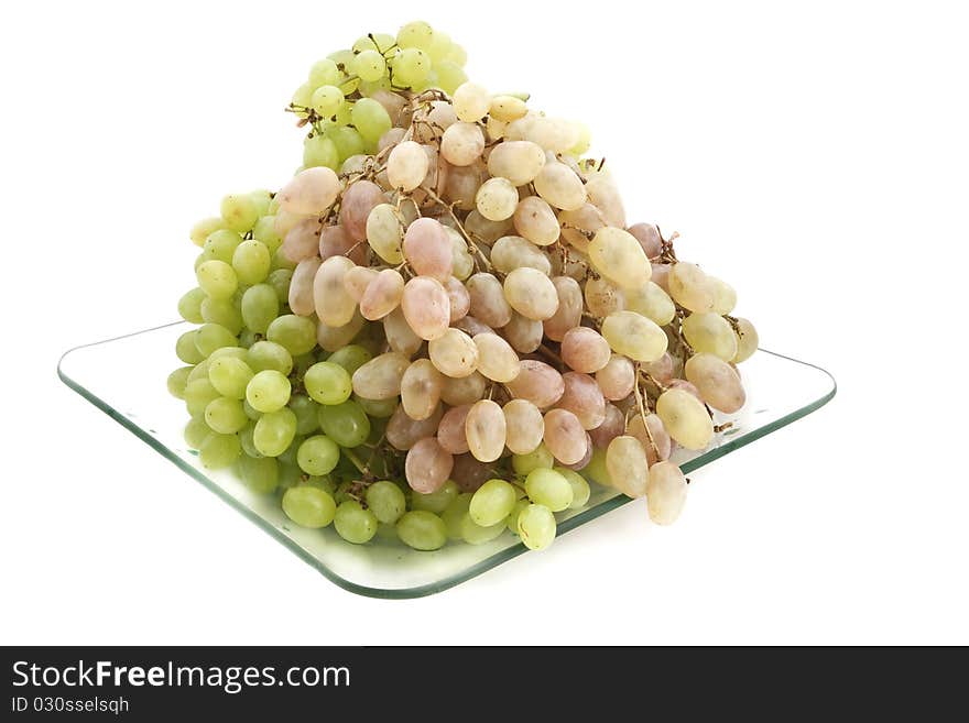 Green and pink grapes on a transparent plate on a white background. Green and pink grapes on a transparent plate on a white background.