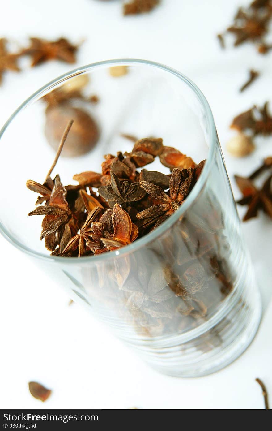 A glass full of anises to be used in spicy cooking with other spices in background. A glass full of anises to be used in spicy cooking with other spices in background.