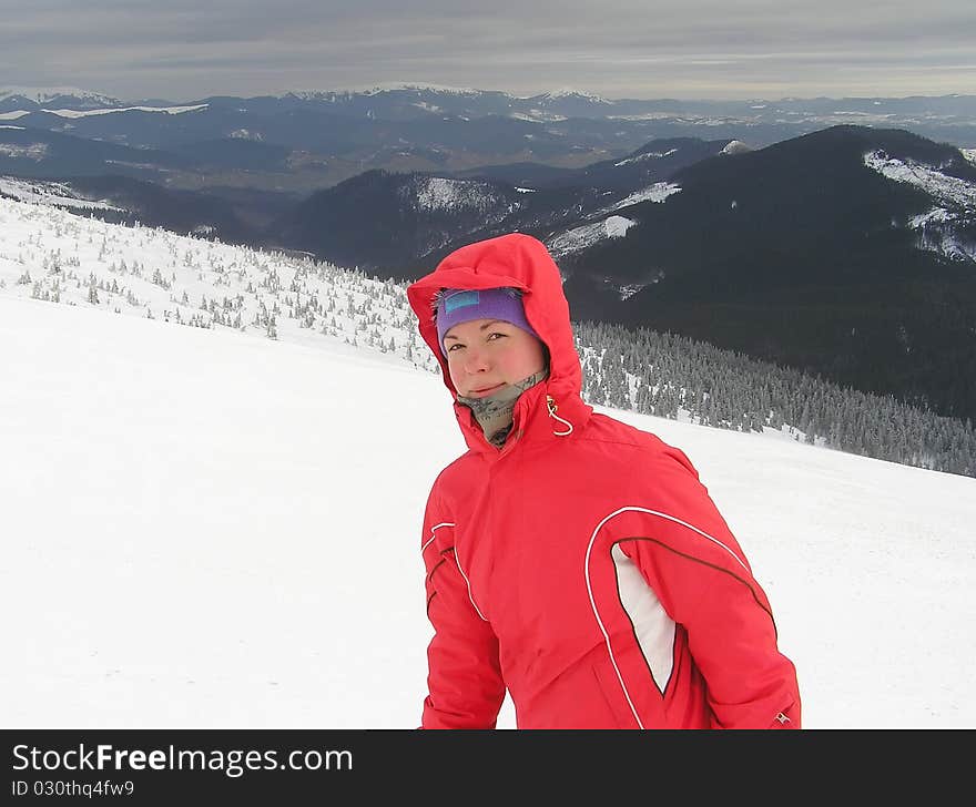 Portrait of young woman in a red ski-wear on the background of mountains. Portrait of young woman in a red ski-wear on the background of mountains